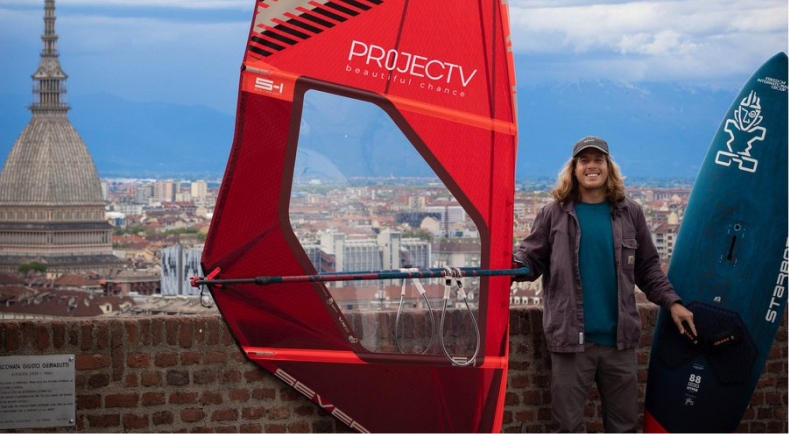 Federico with a surfboard and a red sail
