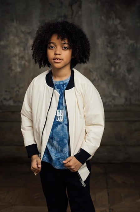 Child in a white NRK87 jacket and blue NRK87 T-shirt
