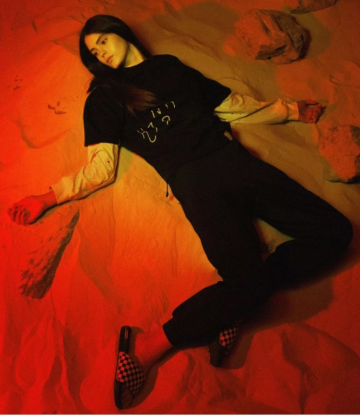 The girl is lying on the sand in NRK87 clothing