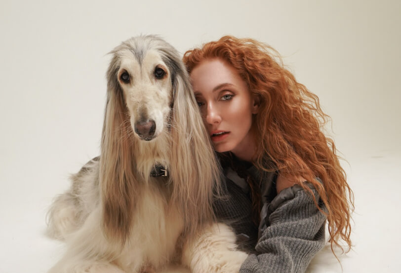 Woman with a hairy dog lying next to her